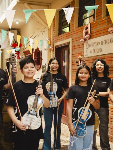 Sechs Jugendliche stehen mit ihren Instrumenten aus Müll im Hof der Musikschule von Cateura, über ihnen bunte Wimpel