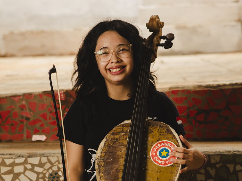 Ayelen mit ihrem Cello Ayelen lacht mit ihrem Cello aus einem Ölfass