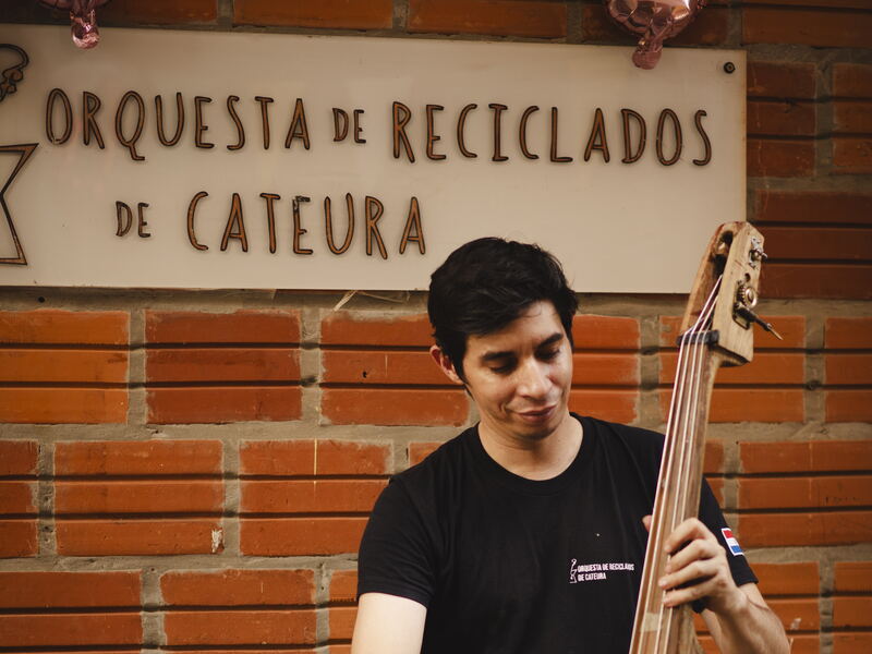 Wilson López unter dem Schild des Orchesters Wilson López spielt Kontrabass unter dem Schild der Orquesta de Reciclados de Cateura